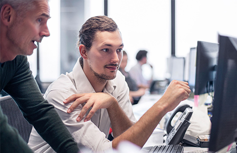 Two men looking at a screen and talking